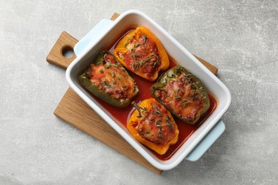 Photo of Tasty stuffed peppers in dish on grey table, top view