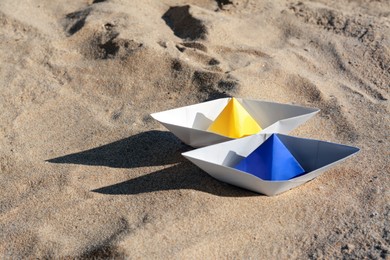Photo of Two color paper boats on sandy beach