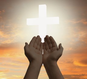 Image of Religion. Christian man praying against sky with glowing cross, closeup