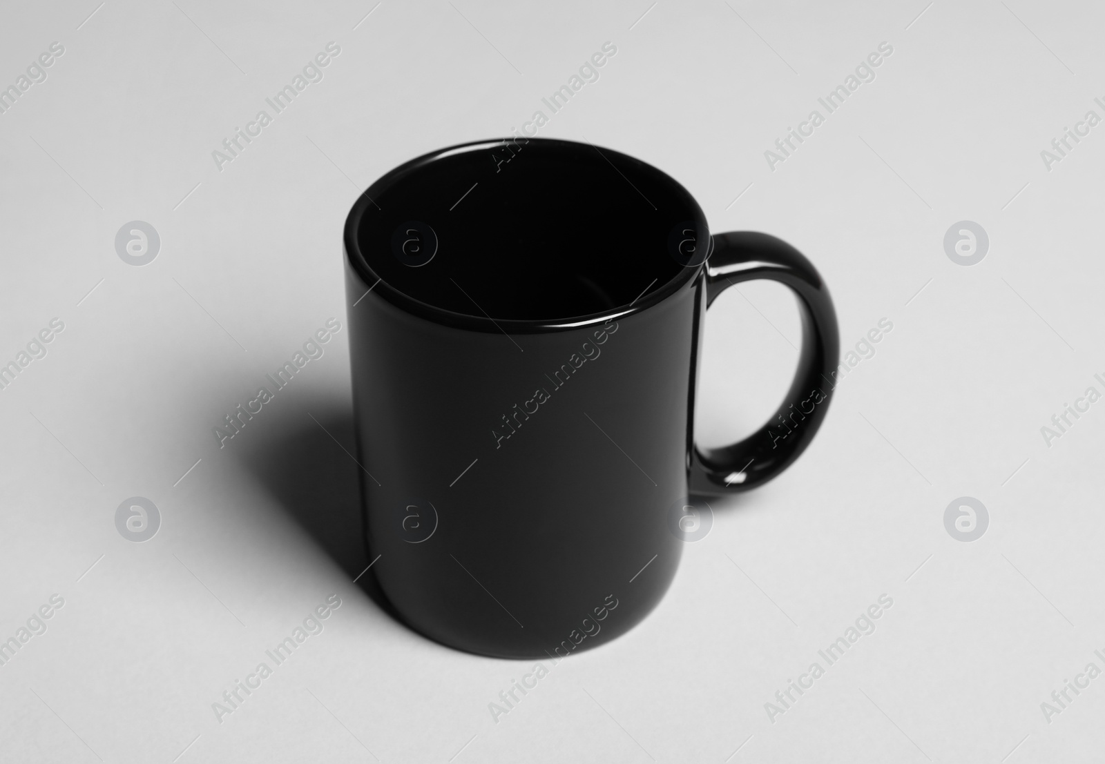 One black ceramic mug on light grey background Photo of One black ceramic mug on light grey background
