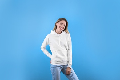 Portrait of woman in hoodie sweater on color background. Space for design