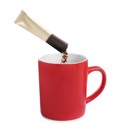 Photo of Pouring aromatic instant coffee into red cup on white background