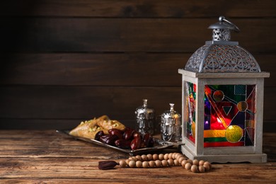 Photo of Arabic lantern and misbaha on wooden table. Space for text