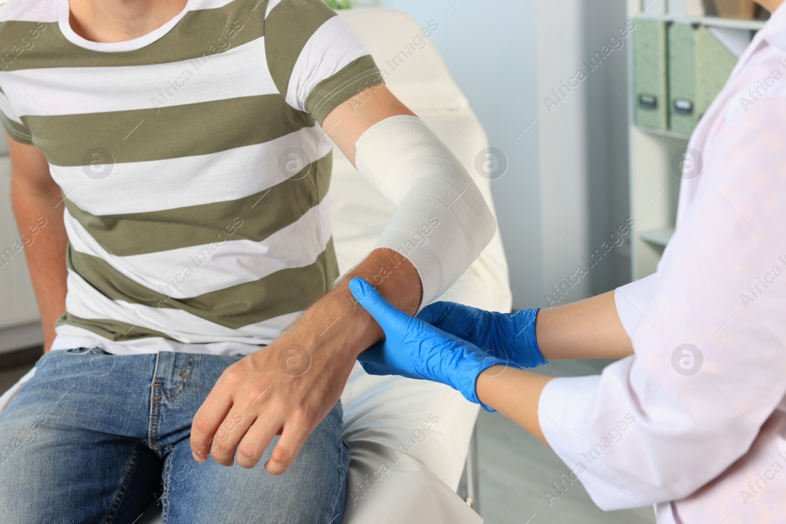 Photo of Doctor applying bandage onto patient's arm at hospital, closeup