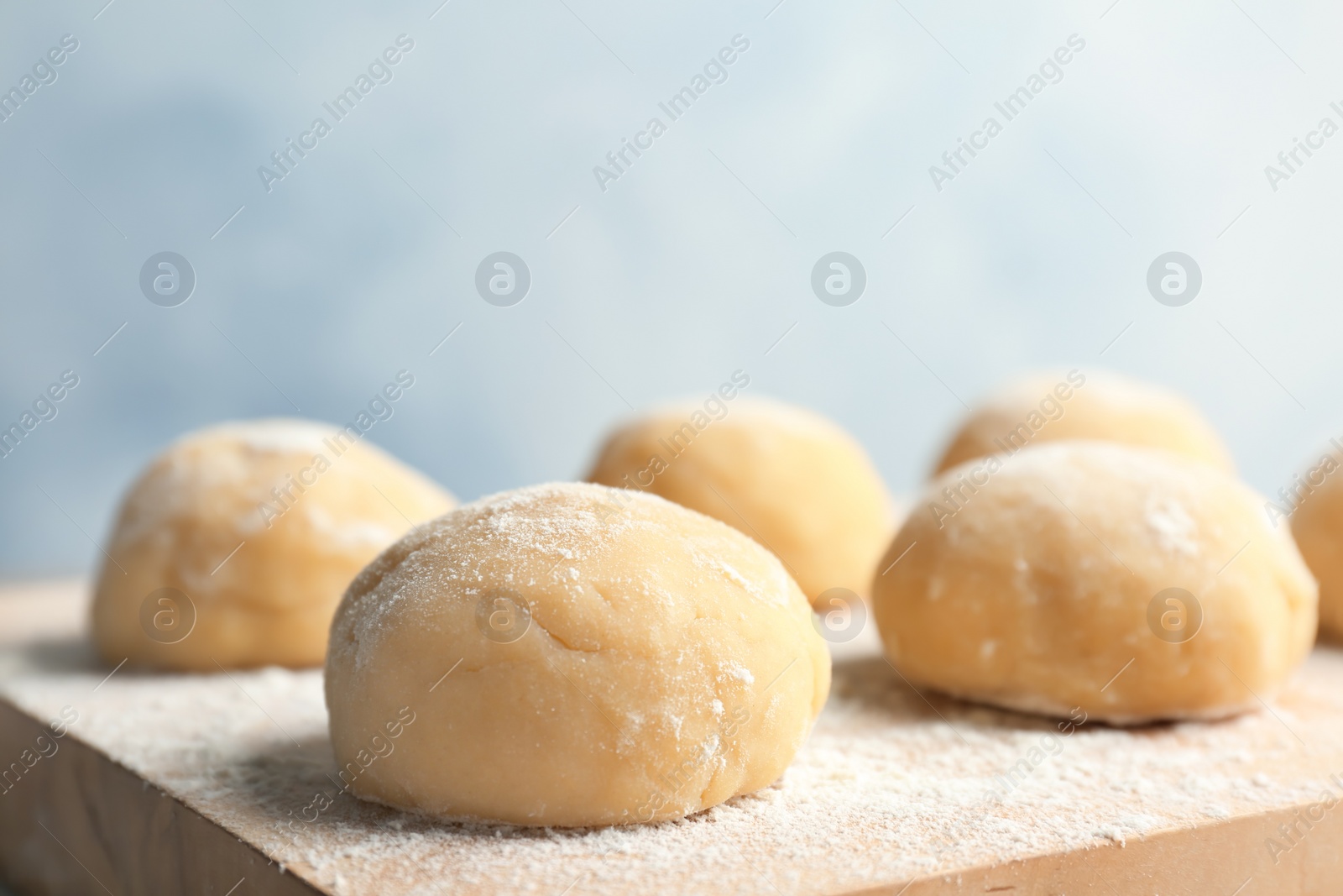 Photo of Fresh raw dough with flour on wooden board