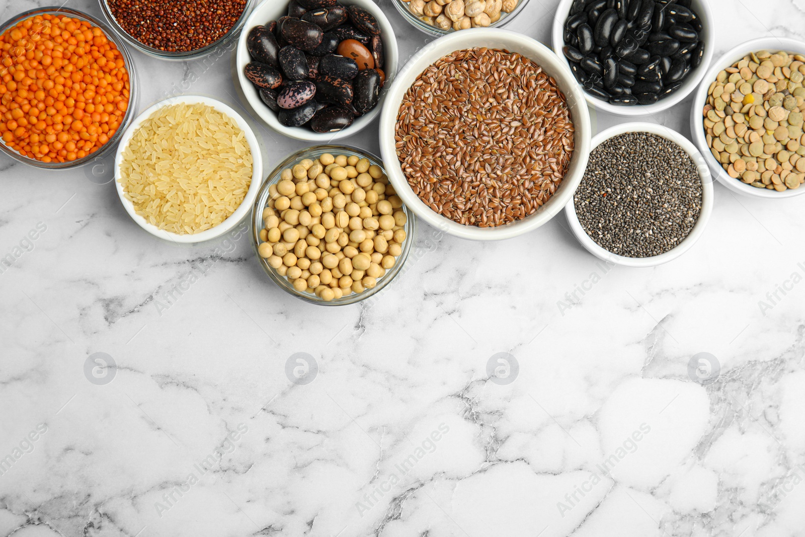 Photo of Different grains, seeds and space for text on white marble table, flat lay. Veggie diet