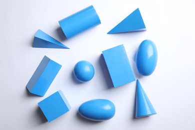 Set of blue wooden geometrical objects on white background, top view. Montessori toy