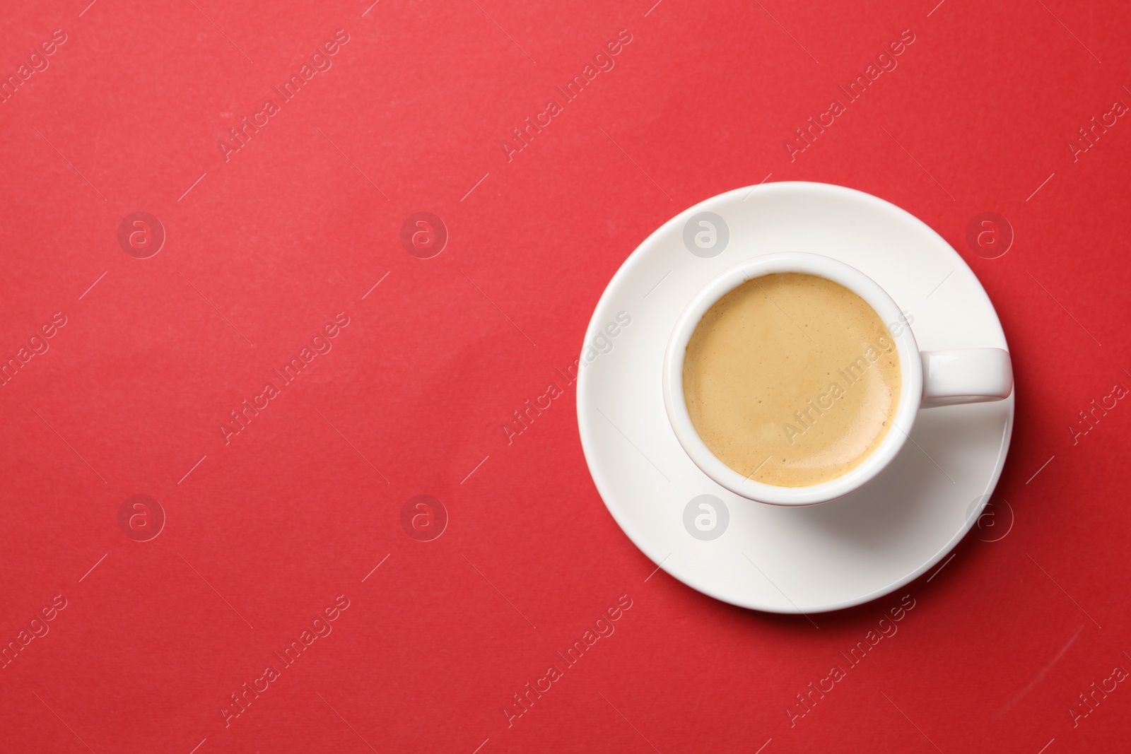 Photo of Aromatic coffee in cup on red background, top view. Space for text