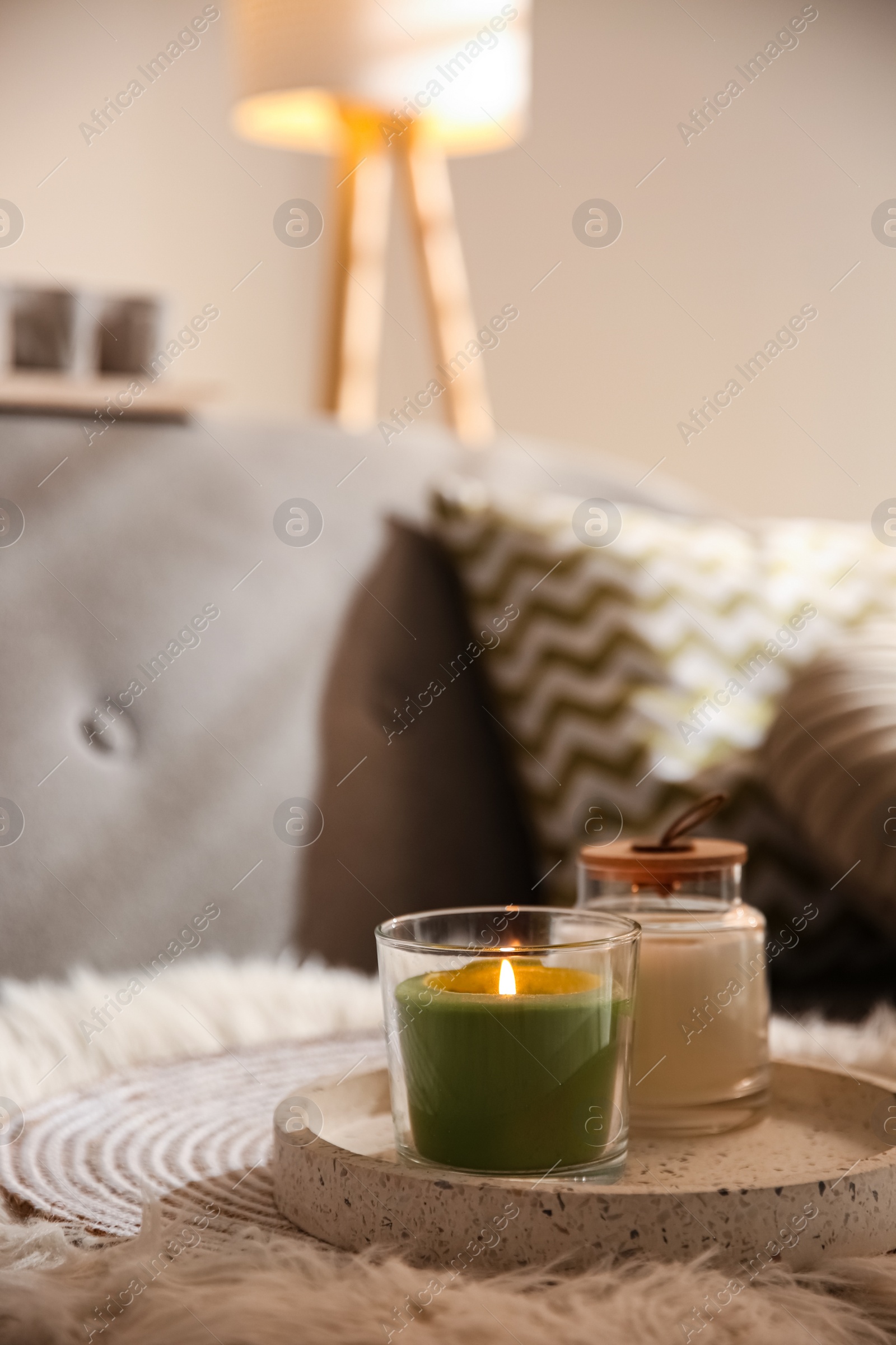 Photo of Aroma candles on grey sofa indoors. Interior design