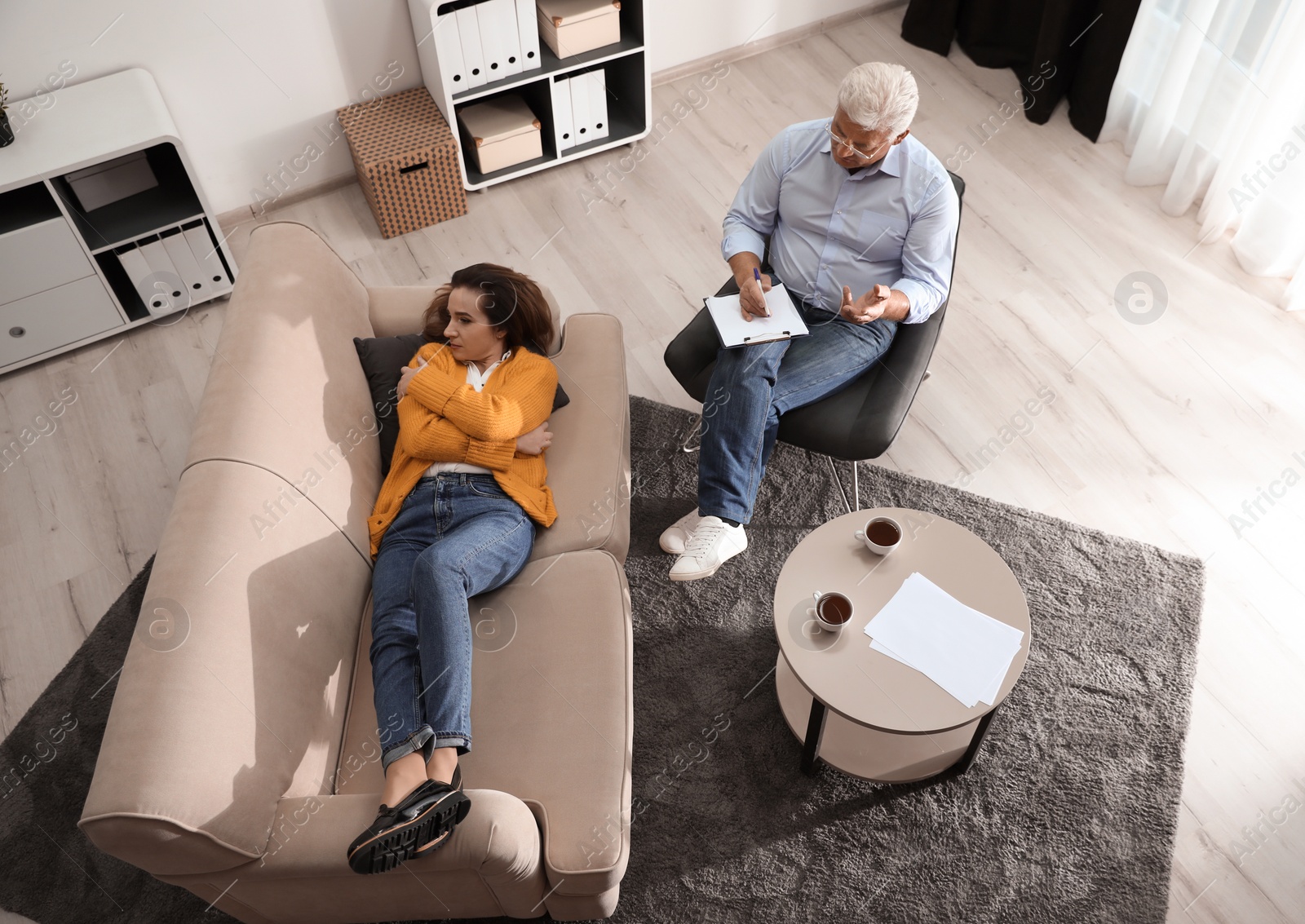 Photo of Professional psychotherapist working with patient in office, above view