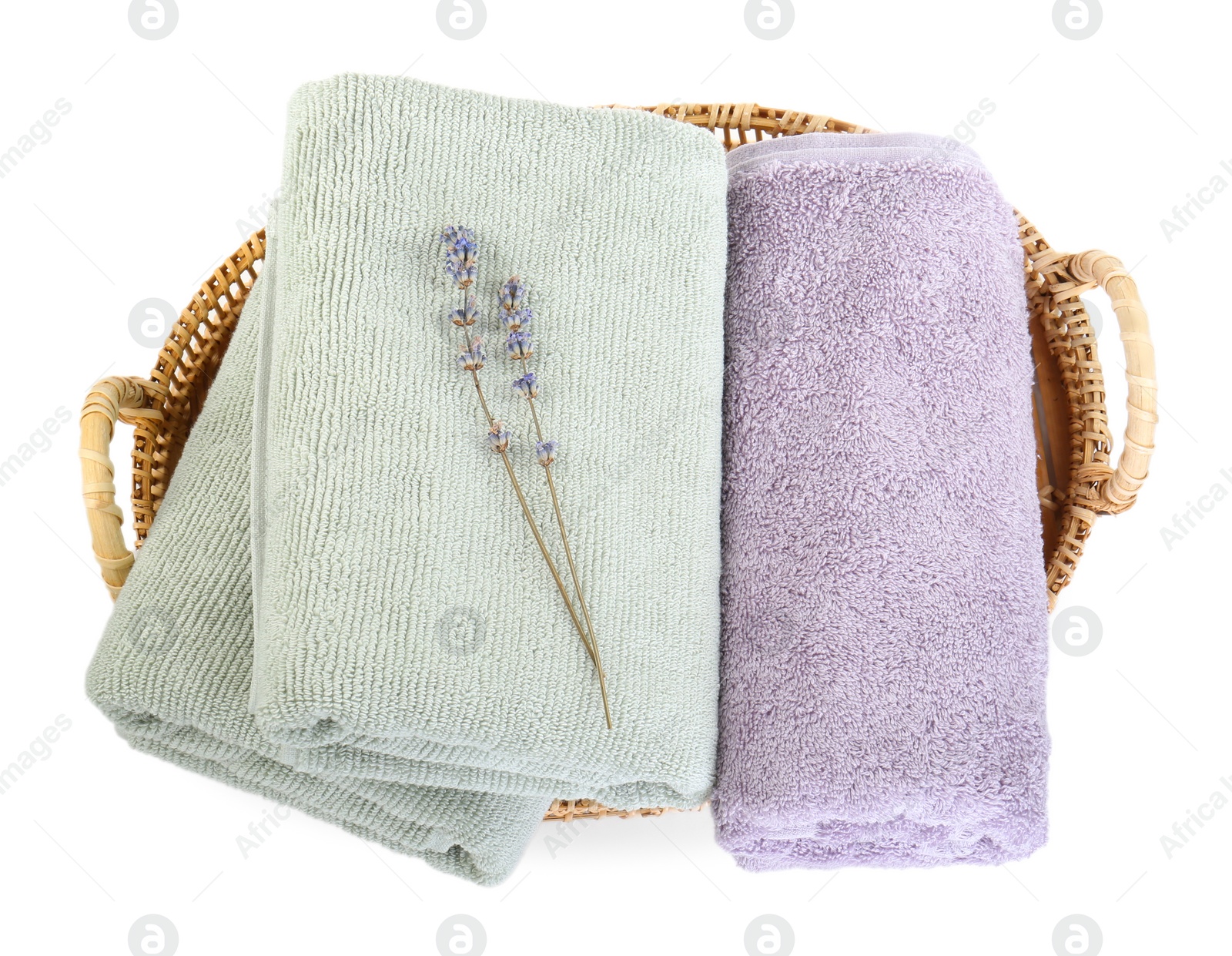 Photo of Basket with different soft towels and lavender flowers isolated on white, top view