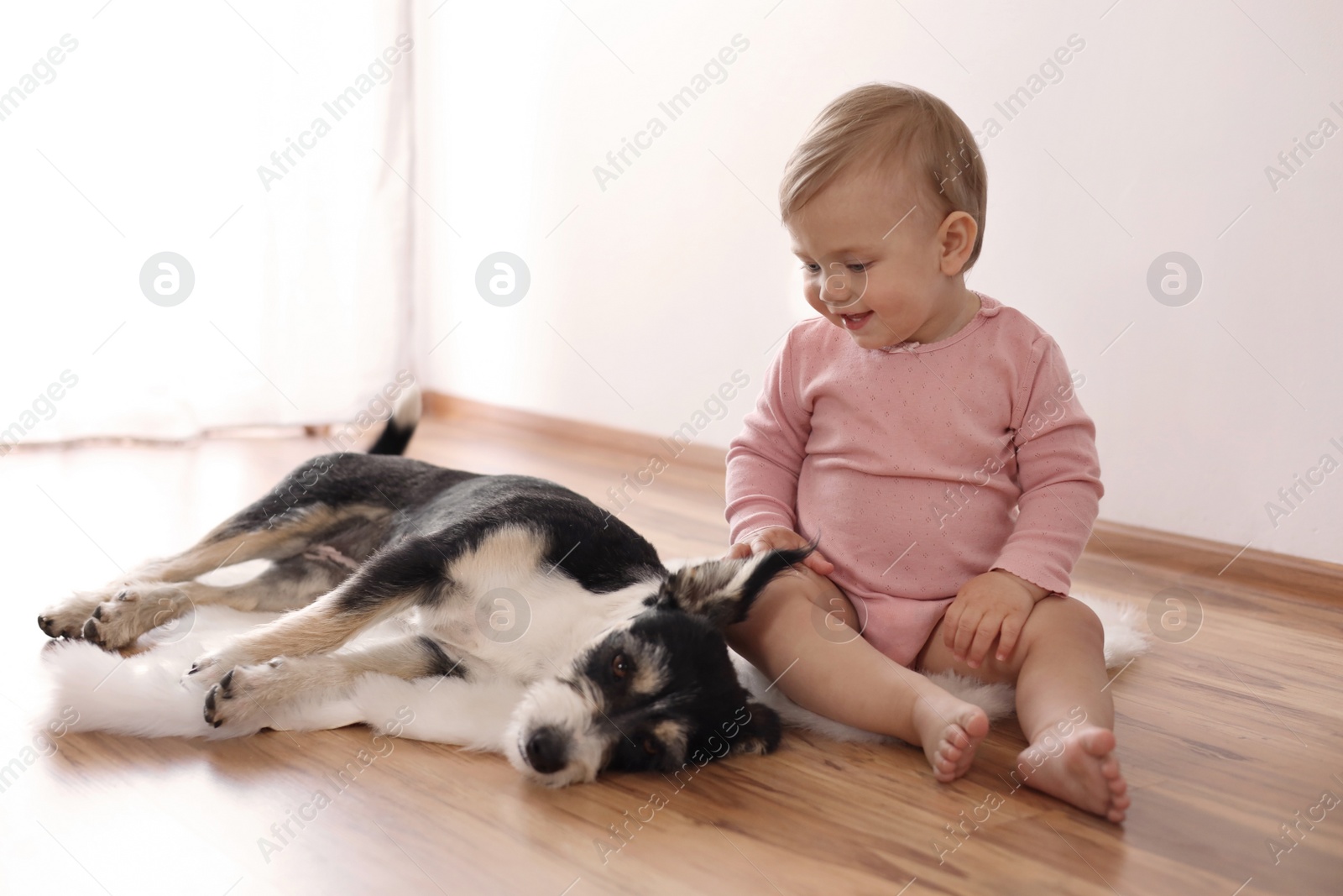 Photo of Adorable baby and cute dog on faux fur rug indoors