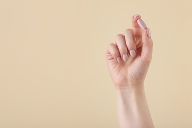 Photo of Woman holding vitamin pill on beige background, closeup with space for text. Health supplement