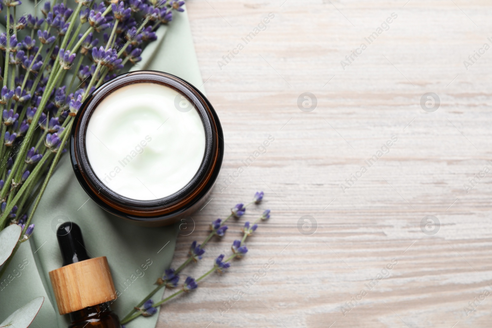 Photo of Jar of hand cream, lavender flowers and cosmetic product on white wooden, flat lay. Space for text