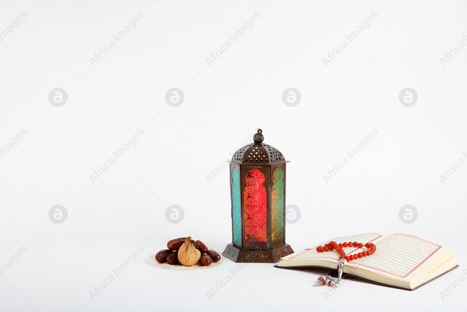 Photo of Muslim lamp, dates, Koran and prayer beads on white background. Space for text