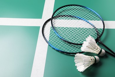 Feather badminton shuttlecocks and rackets on green table. Space for text