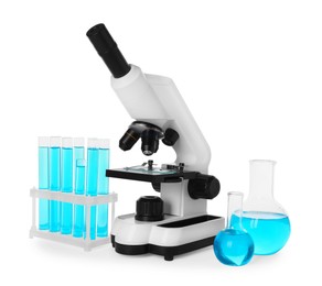 Photo of Laboratory glassware with light blue liquid and microscope isolated on white