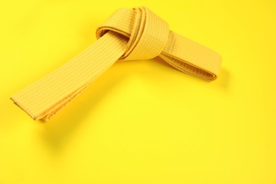 Photo of Karate belt on yellow background, top view. Space for text