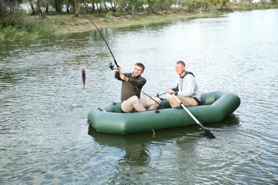 Photo of Friends fishing from boat on river. Recreational activity