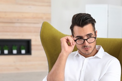 Photo of Portrait of handsome young man sitting in armchair indoors