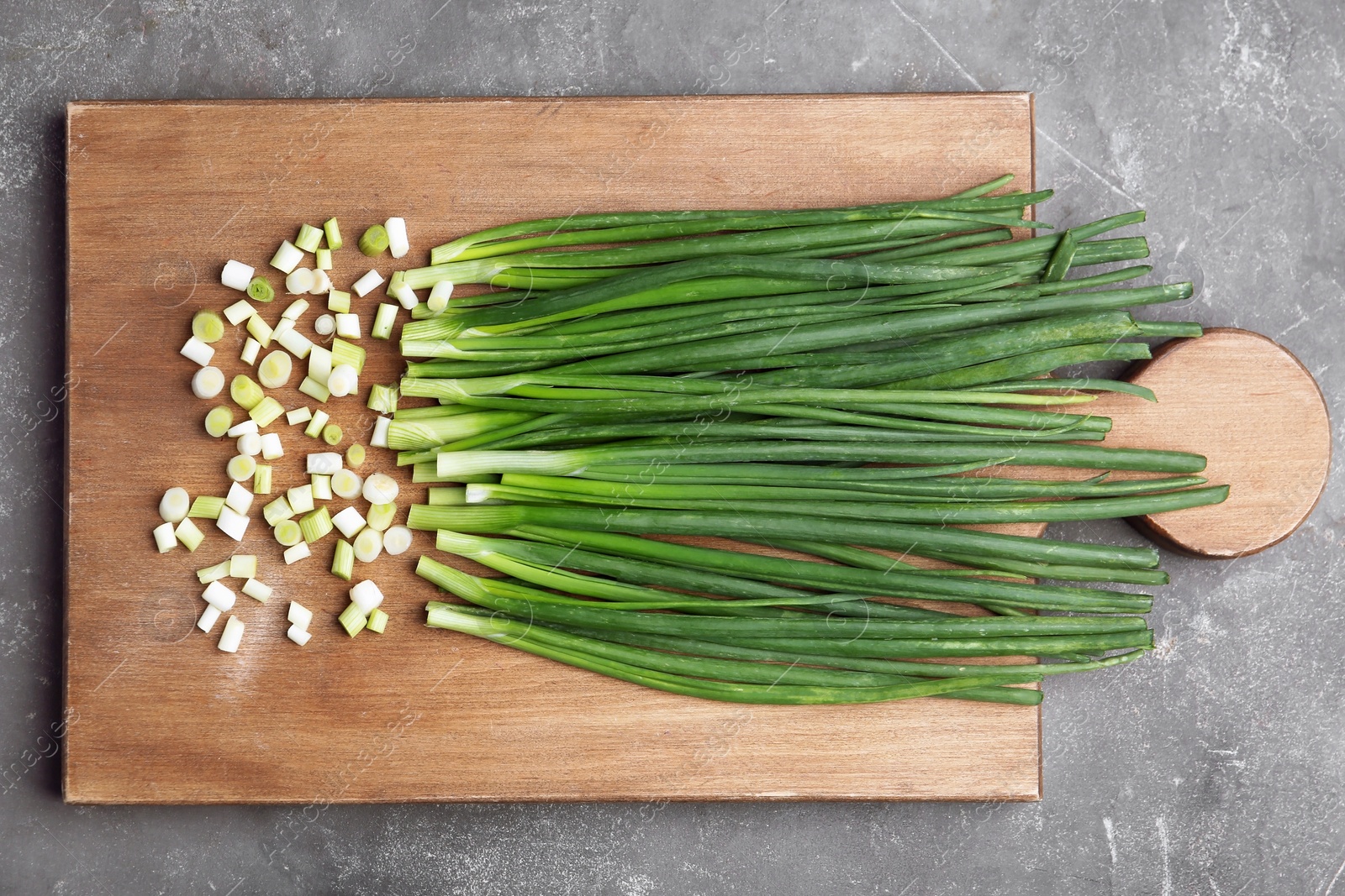 Photo of Fresh green onion on wooden board, top view