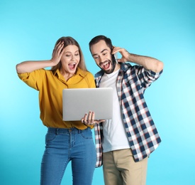 Photo of Emotional young people with laptop celebrating victory on color background