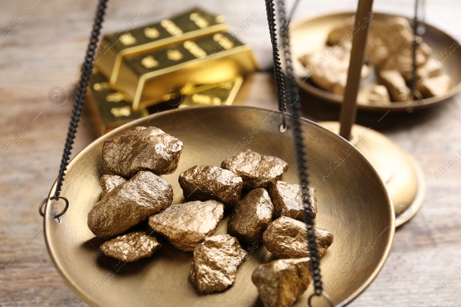 Photo of Scale pan with gold lumps on wooden table, closeup