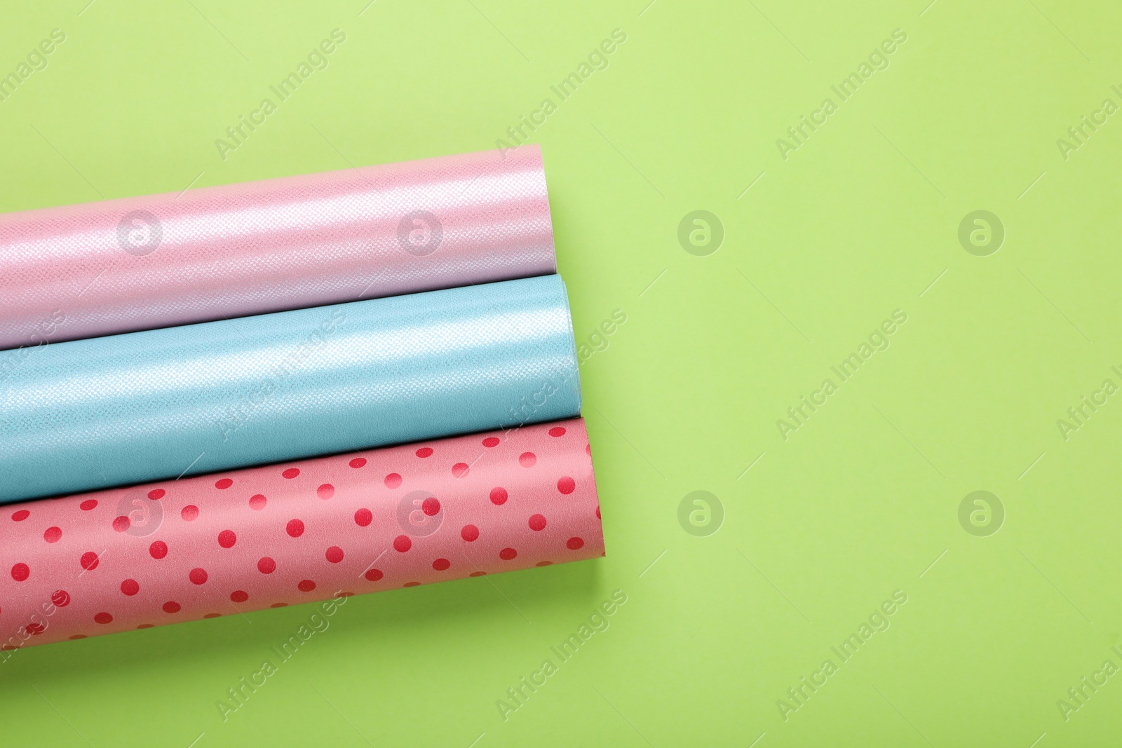 Photo of Rolls of colorful wrapping papers on green background, flat lay. Space for text