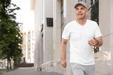 Photo of Handsome mature man running on street, space for text. Healthy lifestyle