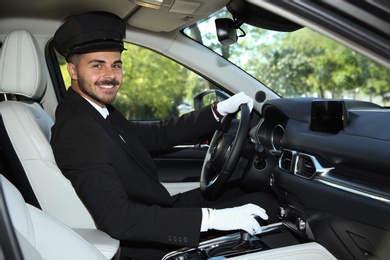 Photo of Young handsome driver in luxury car. Chauffeur service