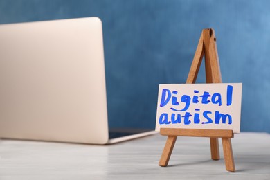 Card with phrase Digital Autism and laptop on white wooden table