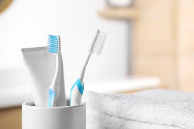 Photo of Plastic toothbrushes, toothpaste and towels on blurred background, closeup. Space for text