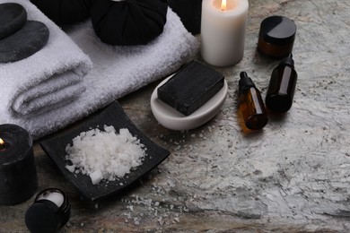 Photo of Composition with different spa products and burning candle on grey textured table. Space for text