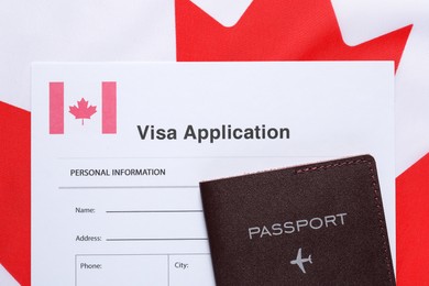Immigration to Canada. Visa application form and passport on flag, top view