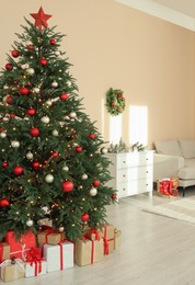 Photo of Beautiful tree decorated for Christmas in room with stylish furniture. Interior design