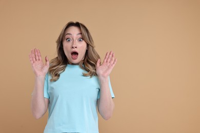 Photo of Portrait of surprised woman on beige background. Space for text