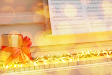Image of Christmas and New Year music. Piano with fairy lights and gift box, bokeh effect