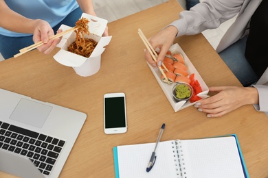 Photo of Office employees having lunch at workplace. Food delivery