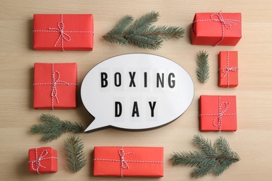 Flat lay composition with Boxing Day sign and Christmas gifts on wooden table