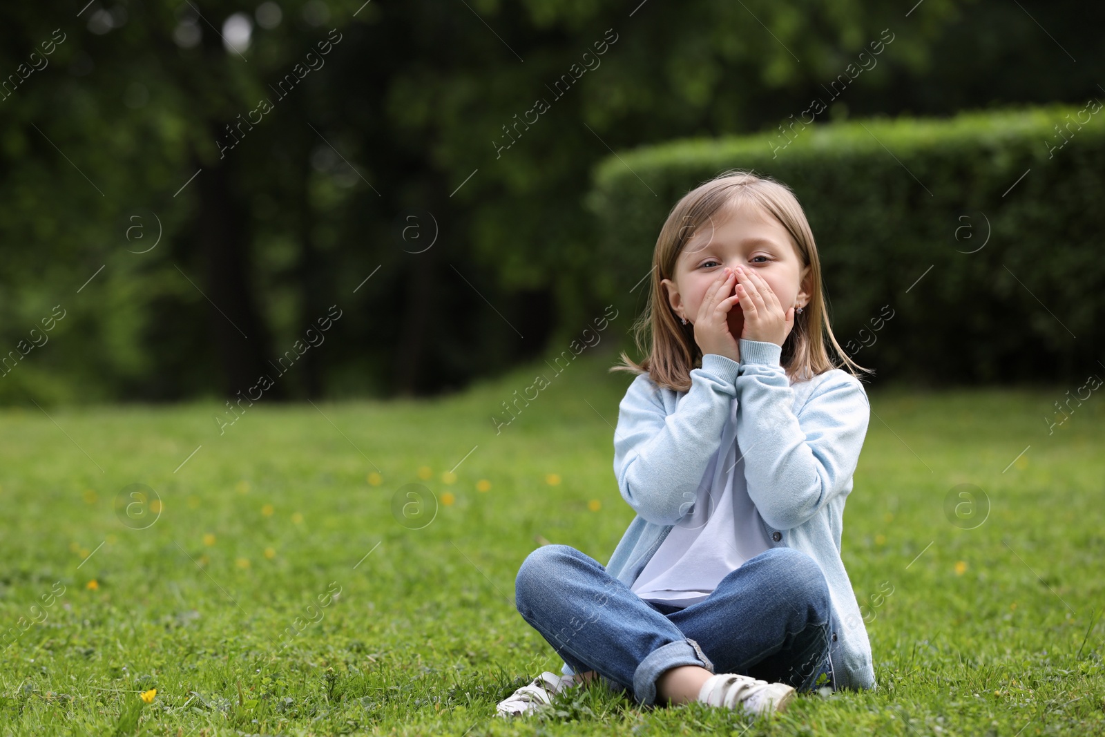 Photo of Little girl suffering from seasonal spring allergy on green grass in park. Space for text