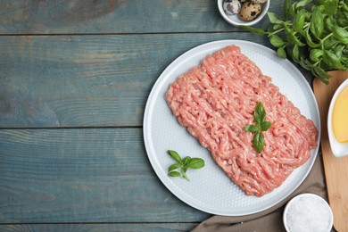 Photo of Raw chicken minced meat and ingredients on light blue wooden table, flat lay. Space for text