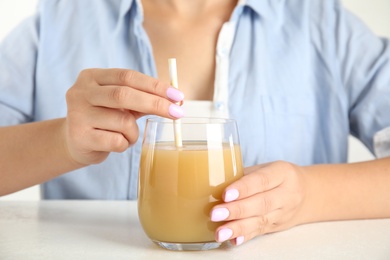 Woman with tasty pear juice at white table, closeup