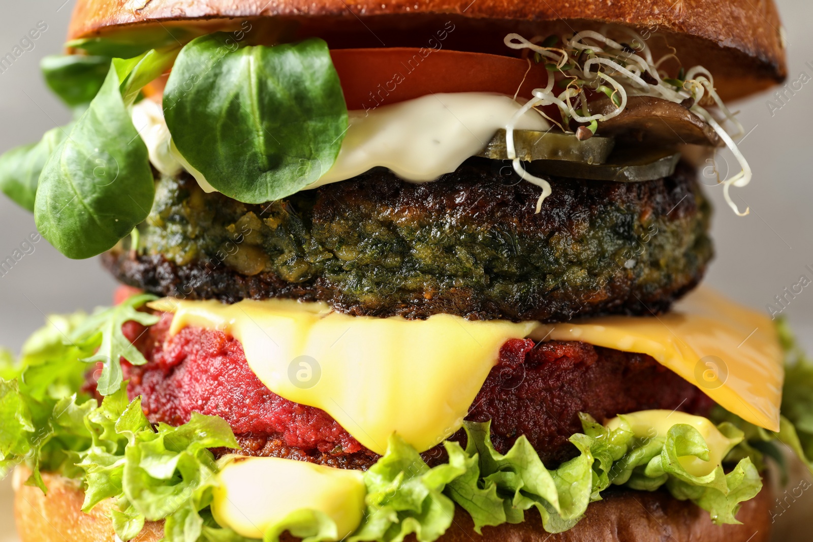 Photo of Vegan burger with beet and falafel patties on grey background, closeup