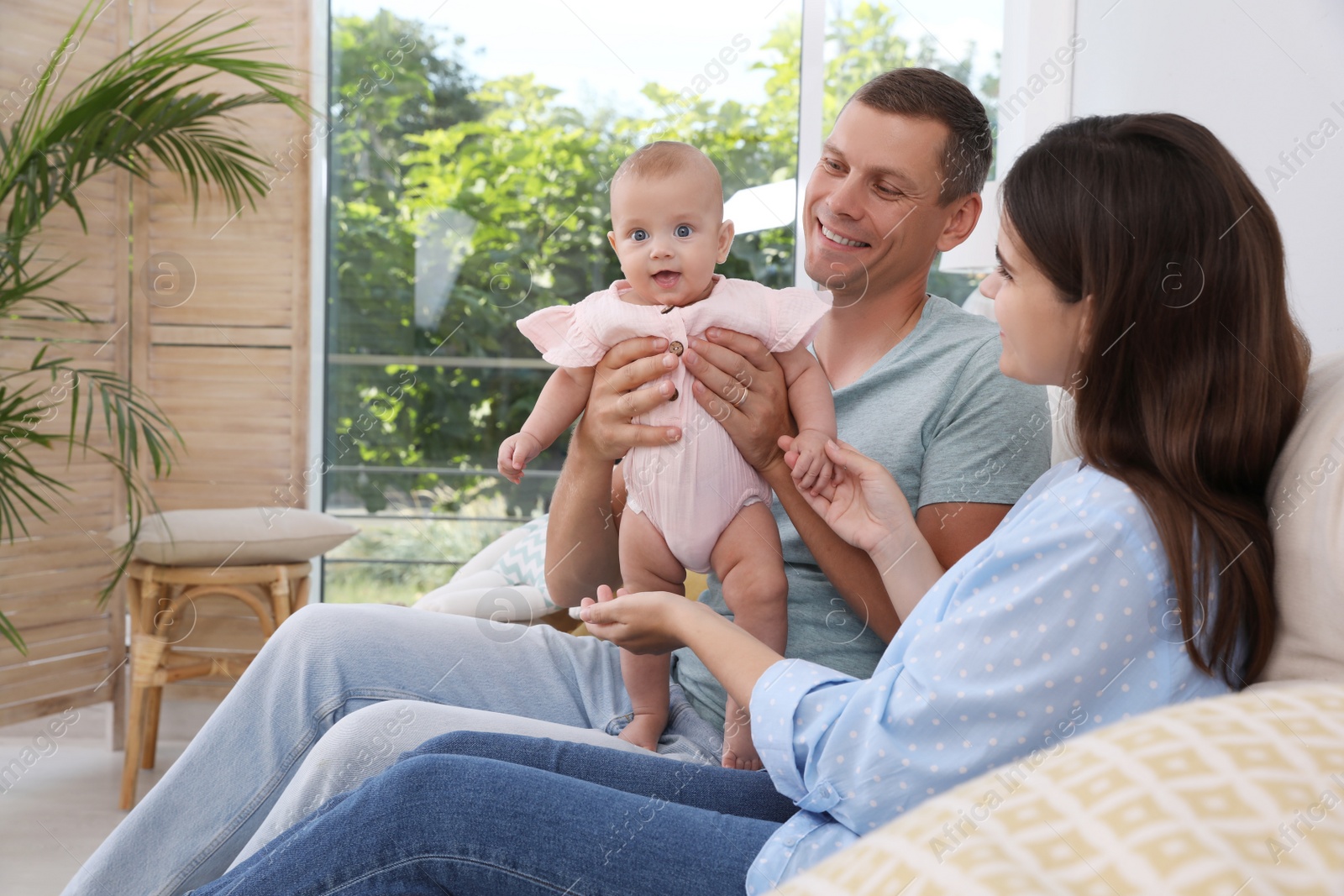 Photo of Happy family with their cute baby in living room at home