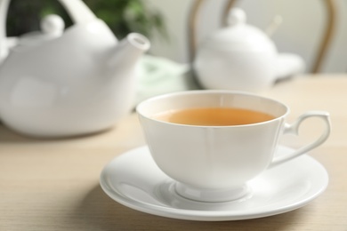 Photo of Cup of hot green tea on wooden table indoors