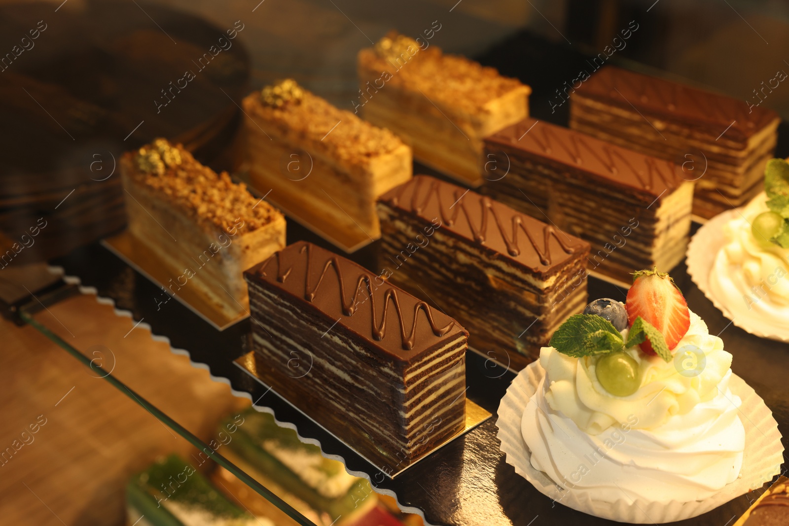 Photo of Different tasty desserts on counter in bakery shop, closeup