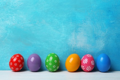 Decorated Easter eggs on table near color wall. Space for text