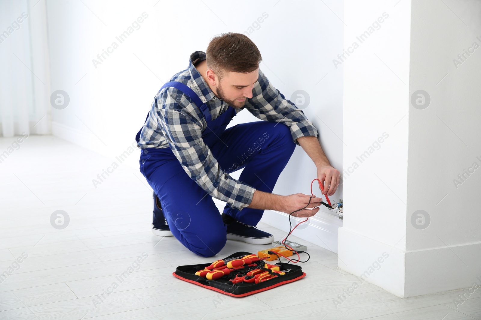 Photo of Professional electrician with tester checking voltage indoors