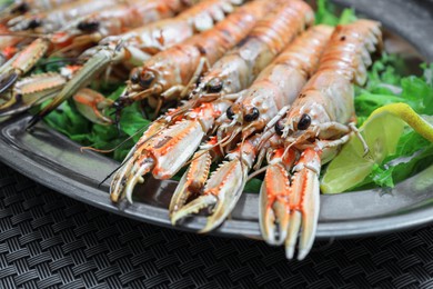 Plate with tasty boiled crayfish and salad on black table, closeup