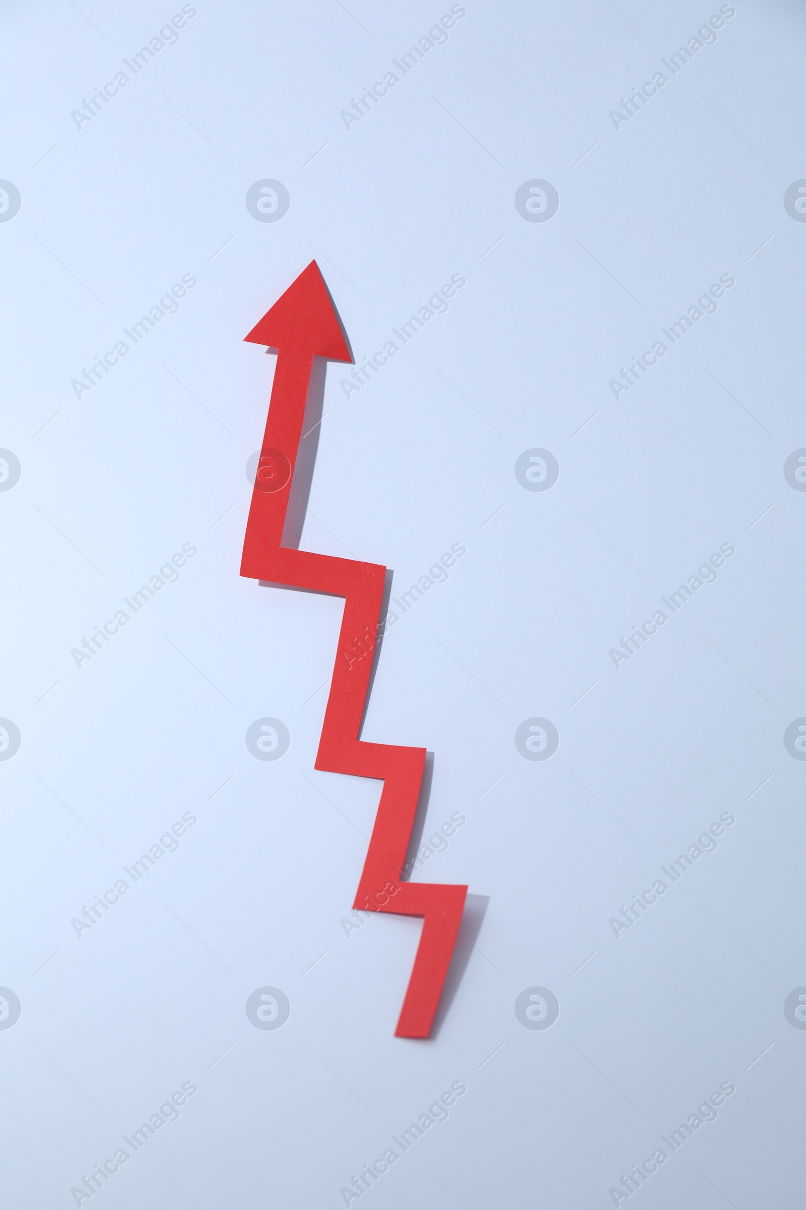 Photo of Red zigzag paper arrow on white background, top view